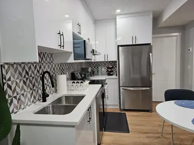 a kitchen with white cabinets and a stainless steel refrigerator at Lovely Brand New 2 Bedroom Suite in Calgary in Calgary