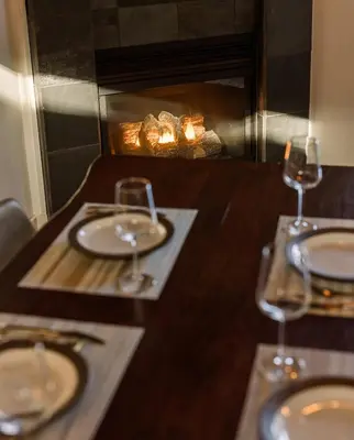 a table with two wine glasses and a fireplace at Island Vista - Waterfront Condo in Tofino