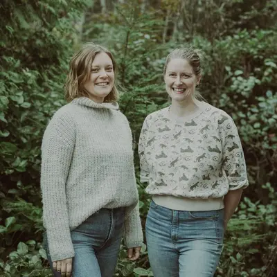two women standing next to each other in a forest at Island Vista - Waterfront Condo in Tofino