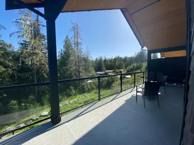 a balcony of a house with a view of the forest at Haven On The Hill in Port Renfrew