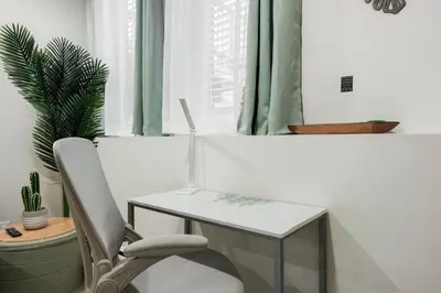 a white desk with a chair next to a window at Tropical Caribbean-Themed Cozy Getaway - King Bed-Free Parking in Calgary