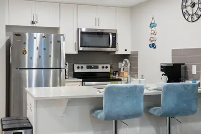a kitchen with a stainless steel refrigerator and blue chairs at Tropical Caribbean-Themed Cozy Getaway - King Bed-Free Parking in Calgary