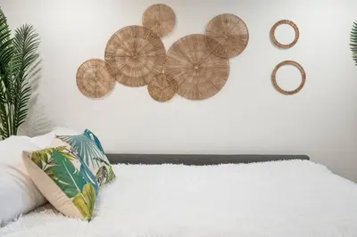 a white wall with a bunch of wooden plates on it at Tropical Caribbean-Themed Cozy Getaway - King Bed-Free Parking in Calgary