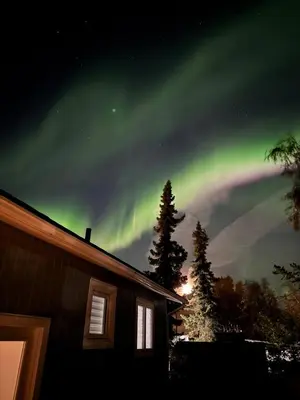 an aurora is dancing in the sky over a house at Modern Downtown Stay in Yellowknife