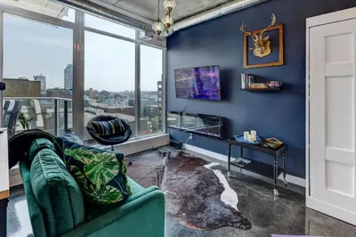 a living room with blue walls and a green couch at Boutique Studio City Views, Patio, Fireplace Voglio Bene in Calgary