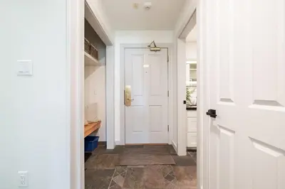 a hallway with a white door and a tile floor at Greystone Lodge by Outpost Whistler in Whistler