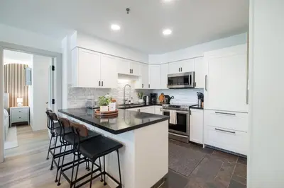 a kitchen with white cabinets and a island with bar stools at Greystone Lodge by Outpost Whistler in Whistler