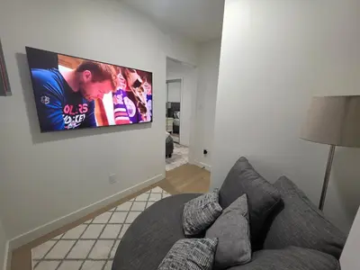 a living room with a couch and a tv on a wall at Amaville- The Cozy Cave - Minutes to WEM & YEG in Edmonton
