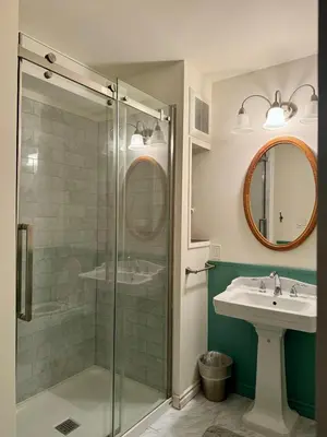 a bathroom with a glass shower and a sink at Blue Cypress Suite- Downtown Tofino in Tofino