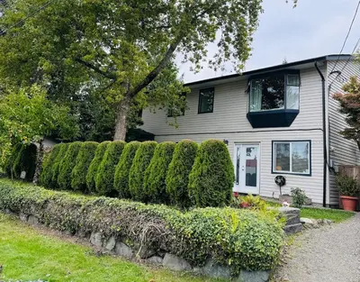 a house with a row of hedges in front of it at Blue Cypress Suite- Downtown Tofino in Tofino