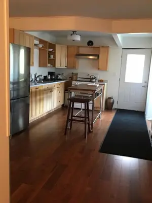 a kitchen with a table and a refrigerator at Blue Cypress Suite- Downtown Tofino in Tofino