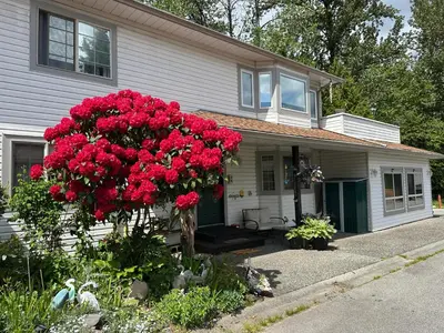 a house with red flowers in front of it at Golden Ears Serenity in Maple Ridge District Municipality
