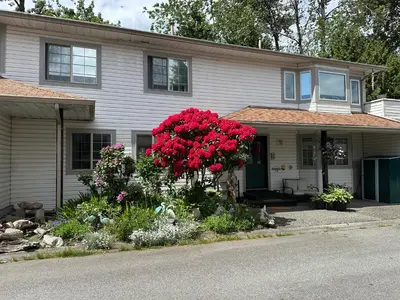 a house with red flowers in the front yard at Golden Ears Serenity in Maple Ridge District Municipality
