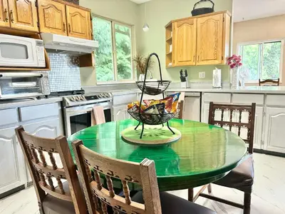 a kitchen with a green table with chairs in it at Golden Ears Serenity in Maple Ridge District Municipality