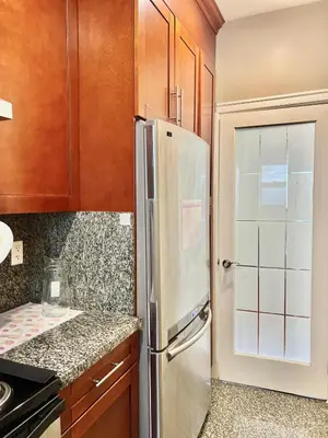 a kitchen with a refrigerator and wooden cabinets at Central & Comfy 1B1B in Vancouver