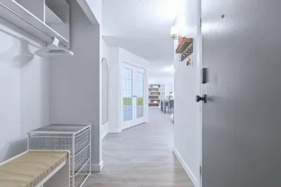 a hallway with white walls and a door and a table at Cozy & Spacious 2BR at Stampede w Parking and AC in Calgary