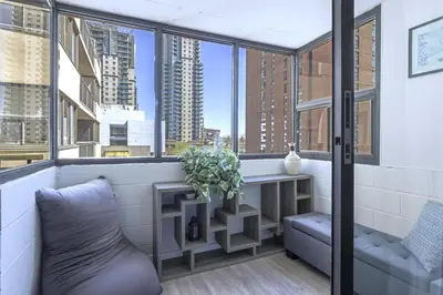 a balcony with a couch and a table and windows at Cozy & Spacious 2BR at Stampede w Parking and AC in Calgary