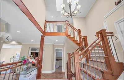 a wooden staircase in a home with a chandelier at Luxury 5BR Villa, Gym, Theater & Ocean Views in West Vancouver