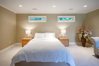 a bedroom with a bed with two night stands and two windows at Luxury 5BR Villa, Gym, Theater & Ocean Views in West Vancouver