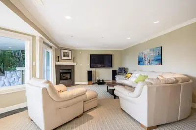 a living room with two white couches and a fireplace at Luxury 5BR Villa, Gym, Theater & Ocean Views in West Vancouver