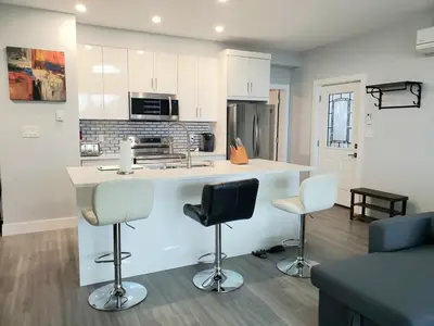 a kitchen with a counter and two bar stools at Winter Deal! Stunning Ocean View Modern 1 BDR Private Entry Suite in Colwood