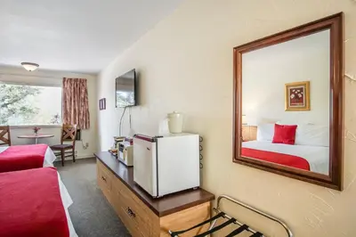 a room with a mirror and a bed and a refrigerator at Gables Motel in Radium Hot Springs
