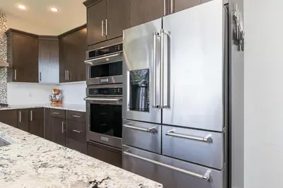 a stainless steel refrigerator in a kitchen with wooden cabinets at Come On In, The Water View Is Waiting For You,,, in Oak Bay
