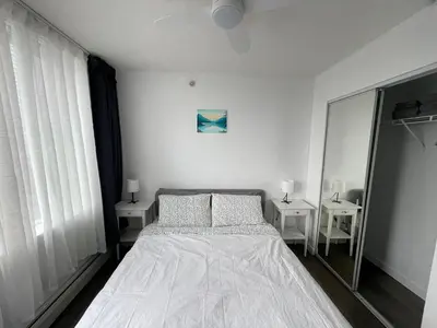 a white bedroom with a bed and two tables at Lucy's House in Vancouver