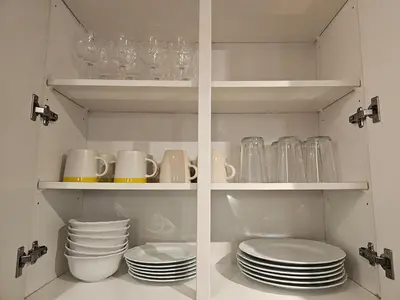 a white cabinet with plates and cups and dishes at Lucy's House in Vancouver