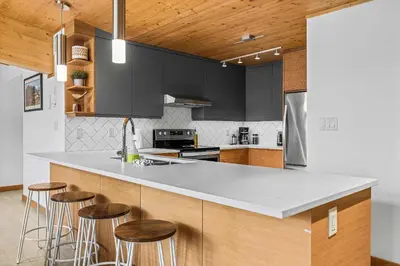 a kitchen with black cabinets and bar stools at Alps #201- LEED Gold Certified in Canmore