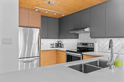 a kitchen with stainless steel appliances and wooden cabinets at Pyrenees #202 - LEED Gold Certified in Canmore