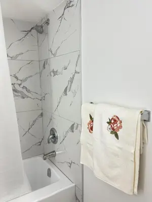 a bathroom with a white shower and a towel with flowers on it at Modern Comfort in West Edmonton in Edmonton