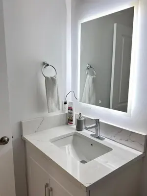 a white bathroom with a sink and a mirror at Modern Comfort in West Edmonton in Edmonton