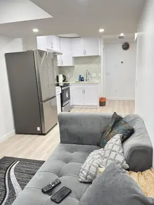a living room with a couch and a kitchen at Modern Comfort in West Edmonton in Edmonton