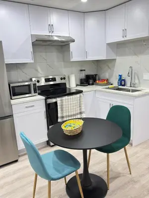 a kitchen with white cabinets and a table and chairs at Modern Comfort in West Edmonton in Edmonton