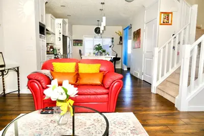 a red chair in a living room with a glass table at Mahogany Loft Retreat - 3 Story Home in Calgary
