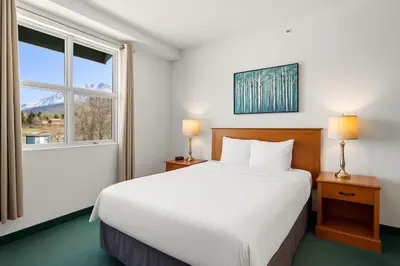 a bedroom with a large white bed and a window at Cozy Hideaway with MTN Views Near DT Canmore and Banff in Canmore
