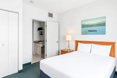 a white bedroom with a bed and a bathroom at Serene 1BR Retreat with Mountain Views in Canmore