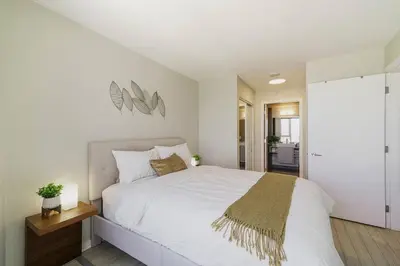a white bedroom with a large white bed and a staircase at Gorgeous Water View Unit in Downtown Vancouver in Vancouver