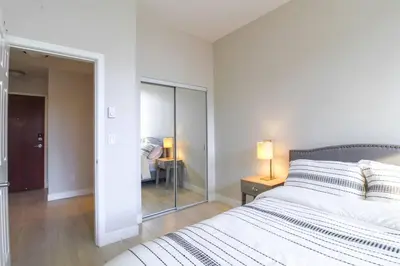 a white bedroom with a bed and a mirror at Beautiful Downtown Unit in Vancouver