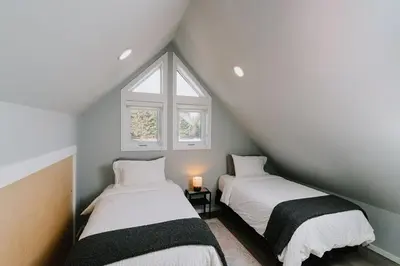 two beds in a attic room with a window at Abraham - Peaceful cabin in historic Nordegg in Nordegg