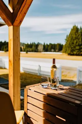 a bottle of wine and two glasses on a wooden table at Coliseum - Get Back to Nature in Nordegg