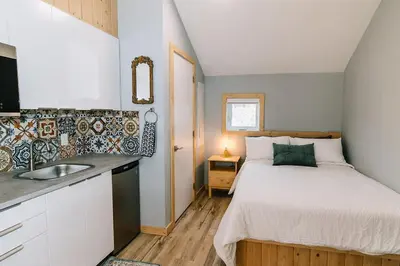 a small bedroom with a bed and a sink at Trailhead Tuck-Inn in Nordegg