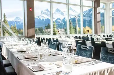 a dining room with tables and chairs with mountains in the background at Chic Rockies Getaway - Pool & Hot Tub - King Bed - BBQ! in Canmore