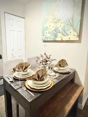 a table with plates and napkins on top of it at Stylish Downtown Condo near Rogers Place l Parking, Gym, Balcony & Kitchen in Edmonton
