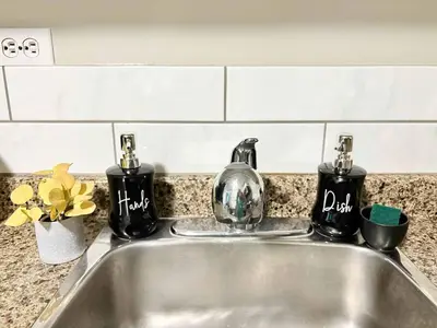 a kitchen sink with two soap dispensers on it at Stylish Downtown Condo near Rogers Place l Parking, Gym, Balcony & Kitchen in Edmonton