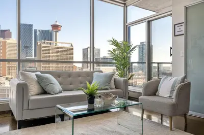 a living room with a couch and a table and windows at The Prime Downtown | Luxe Condo + Free Parking in Calgary