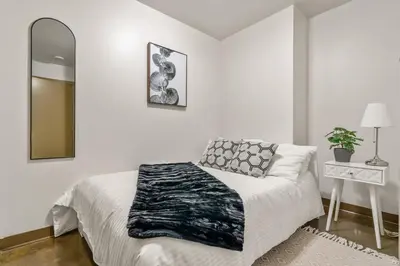 a white bedroom with a bed and a mirror at The Prime Downtown | Luxe Condo + Free Parking in Calgary