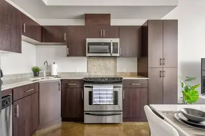 a kitchen with stainless steel appliances and wooden cabinets at The Prime Downtown | Luxe Condo + Free Parking in Calgary