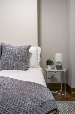 a bedroom with a bed and a table with a lamp at The Chic Downtown Residence | Luxe + Free Parking in Calgary